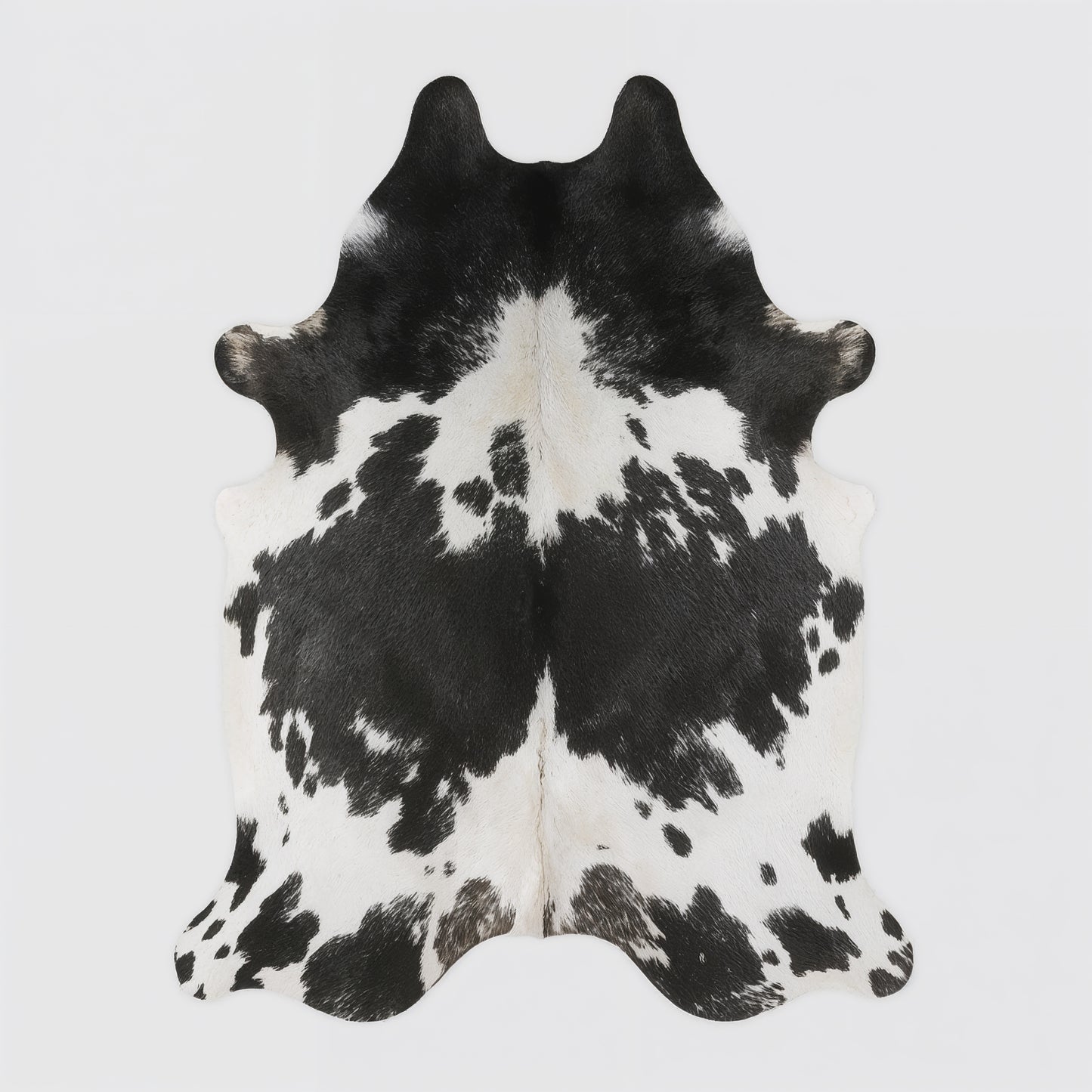 Black and white cowhide rug on a light gray background