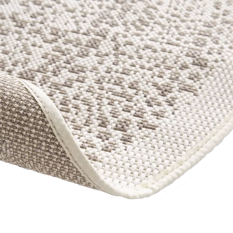 Close-up of a textured beige rug corner on a white background