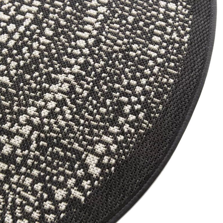 Close-up of a textured black and gray circular mat on a white background