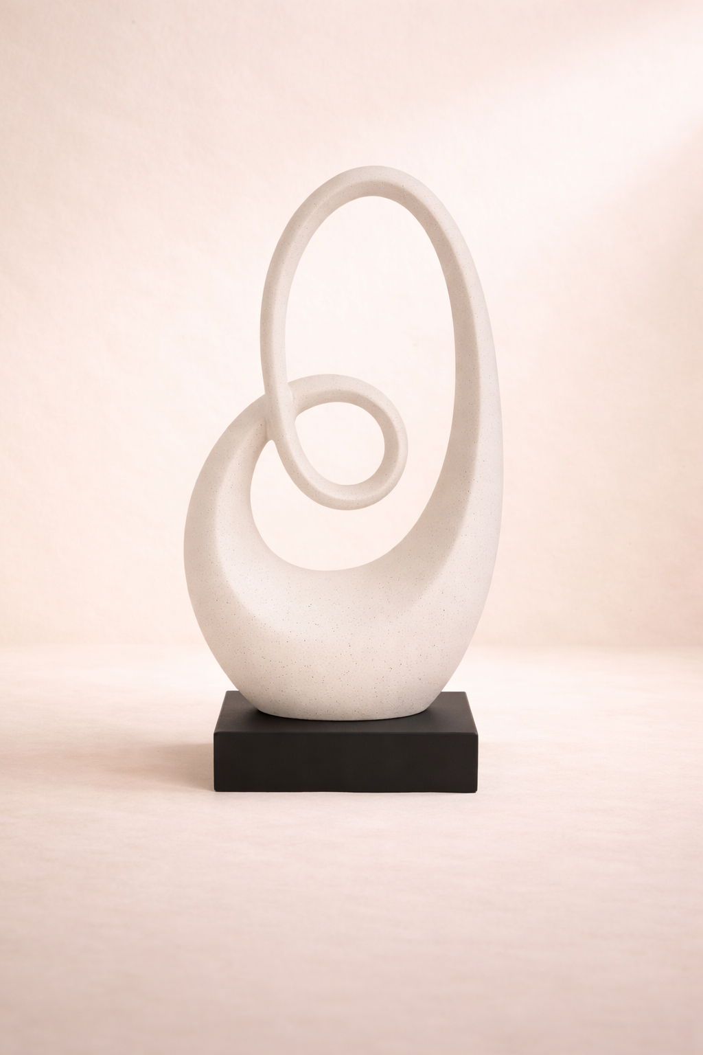 White abstract sculpture on a black base against a pink background
