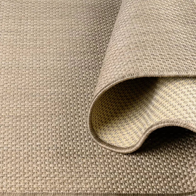 Close-up of a textured beige rug with a folded edge.