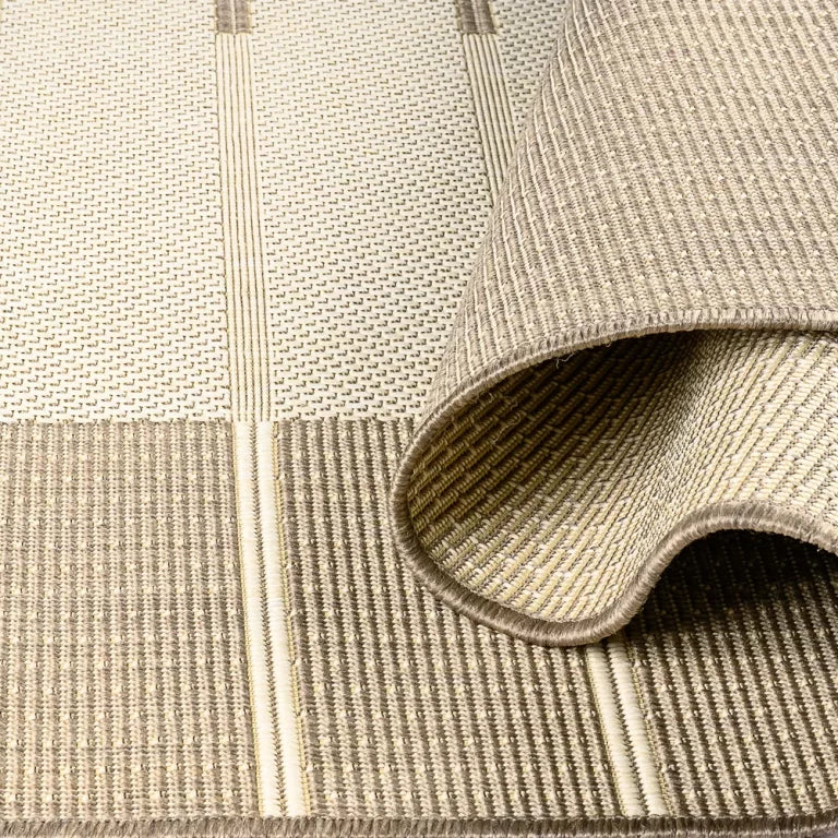 Close-up of a textured beige and brown rug with a visible pattern.