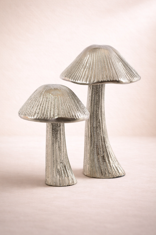 Two silver mushroom-shaped decorative items on a light pink background
