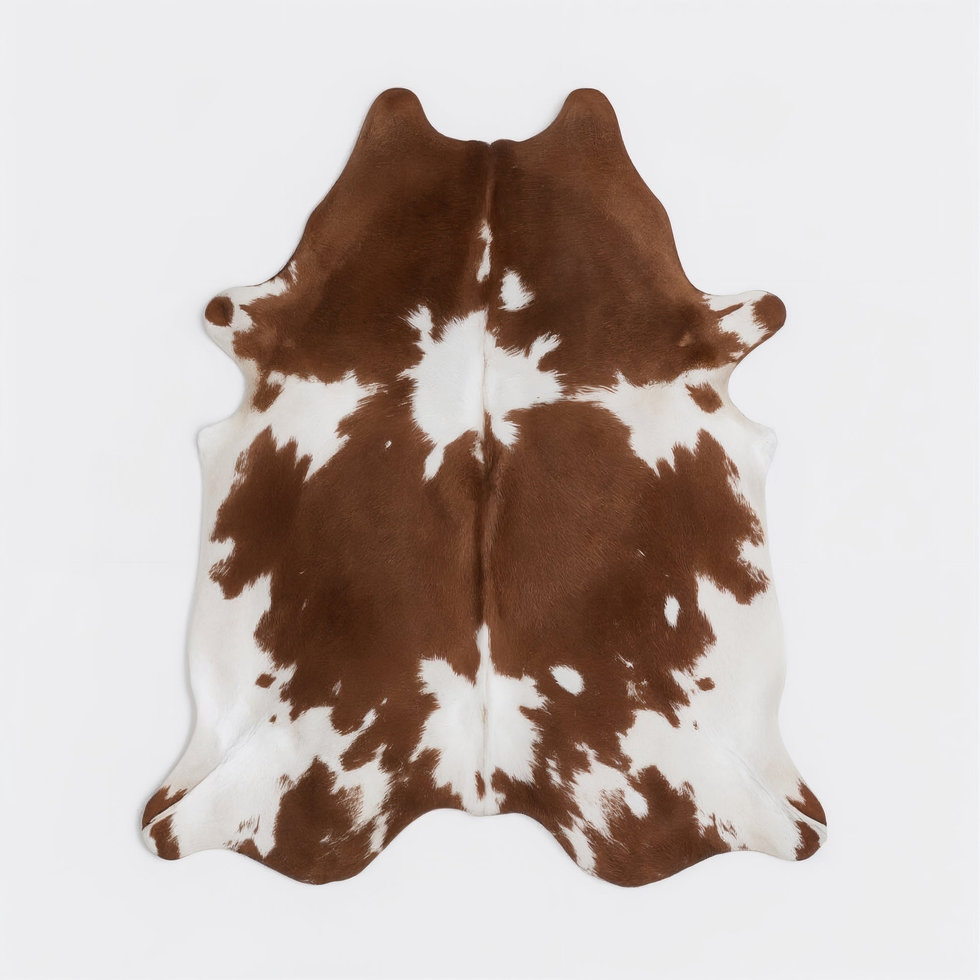 Brown and white cowhide rug on a light gray background
