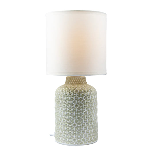Table lamp with textured ceramic base and white shade on a white background