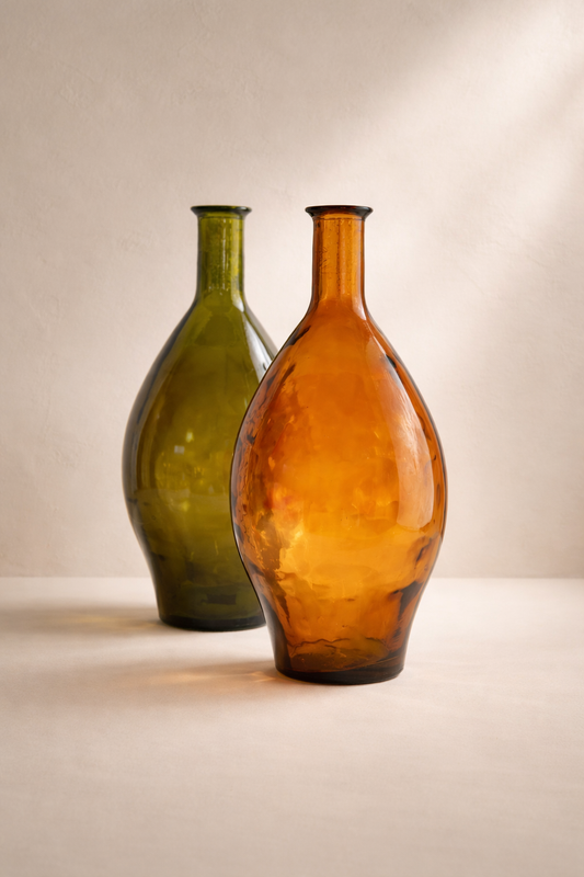 Two glass bottles, one green and one orange, on a neutral background