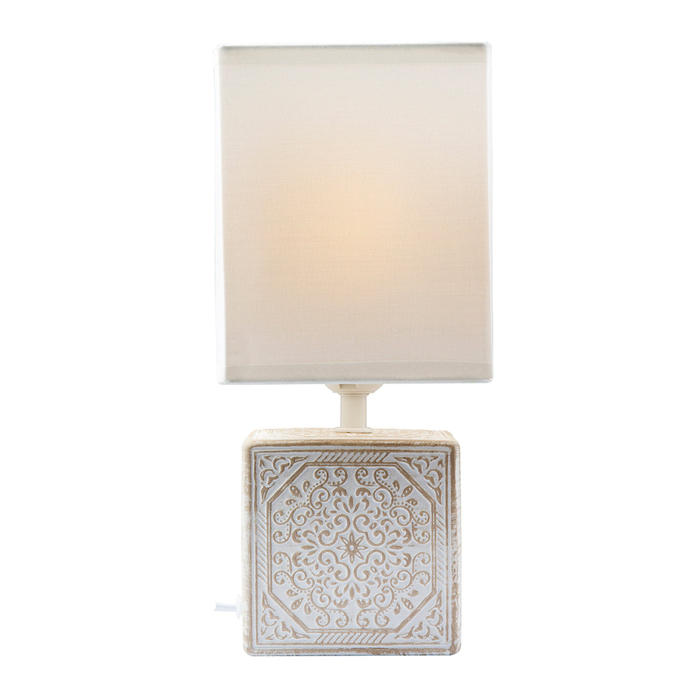 Table lamp with decorative square base and white shade on a white background