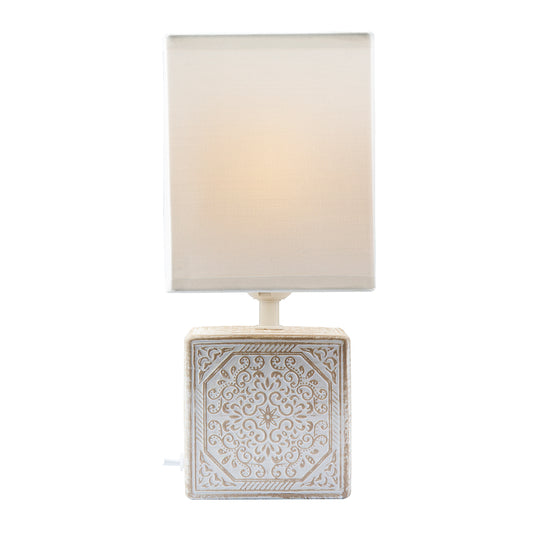 Table lamp with decorative square base and white shade on a white background