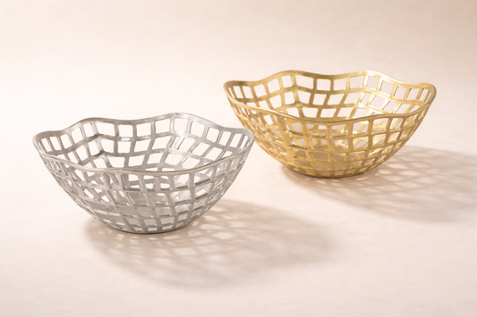 Two woven baskets, one silver and one gold, on a light background