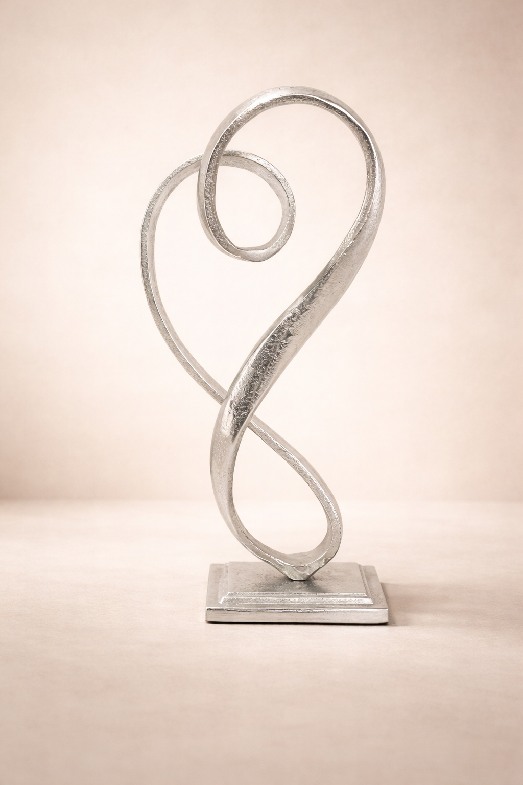 Silver abstract sculpture on a beige background