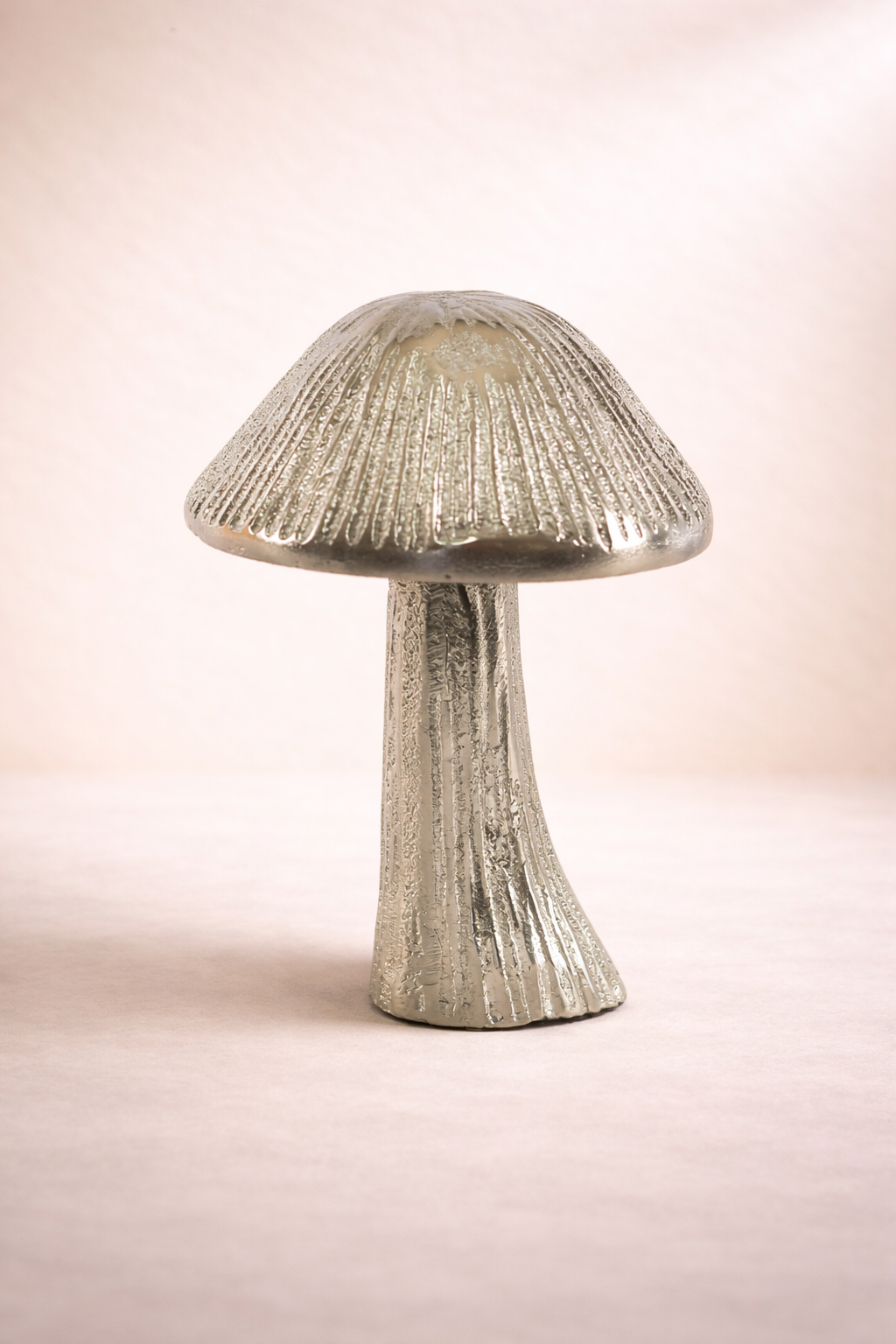 Mushroom-shaped lamp with textured surface on a light pink background