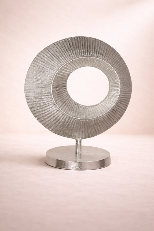 Decorative metallic object with concentric circles on a pink background