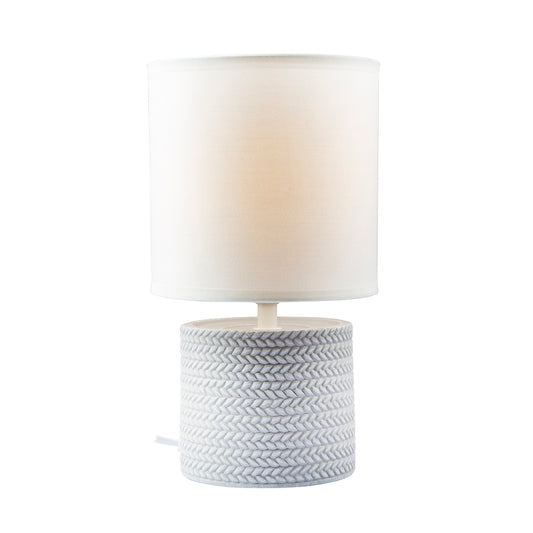 Table lamp with a textured gray base and white shade on a white background